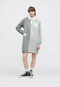 Pilkas medvilninis suknelė su apykakle, kontrastingų atspalvių ir grafinių spaudinių krūtinės srityje. Derinama su juodais sportbačiais ir baltais kojiniais.