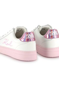 Bílé kožené tenisky s růžovými gumovými podrážkami, holografickými akcenty na podpatku a podpisovým logem Karla v růžové barvě na boku, navržené pro děti.