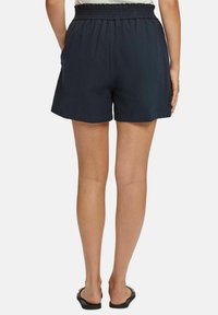 Laivastonsiniset shortsit joustavalla, smokkauksella varustetulla vyötäröllä. Kangas on kevyt ja sileä, siinä on sivutaskut ja rento istuvuus.