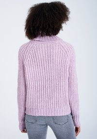 Ljusrosa stickad tröja med hög krage, ribbat mönster och sänkt axeldesign. Bakpartiet har en avslappnad passform och långa ärmar.