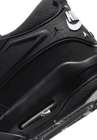 Baskets de sport noires avec une tige en tissu noir texturé, des accents synthétiques lisses et une unité d'air visible dans la semelle. Présente des détails de logo.