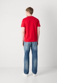 Punane puuvillane T-särk lühikeste varrukatega, ümmarguse kaelusega; koos helesiniste denim teksadega, millel on sirge lõige ja tagumised taskud.