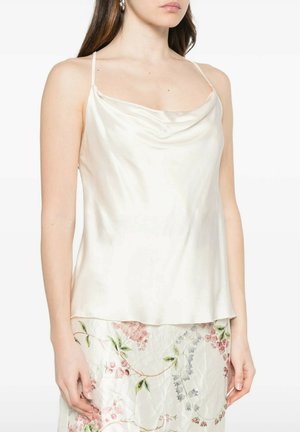 Donna che indossa un top smanicato in raso crema con scollo a cappuccio e gonna con motivo floreale con foglie verdi e fiori rosa.