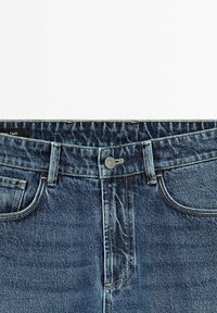 Mörkblå denimjeans med knäppning, fem fickor och subtil avblekning över hela tyget som visar en klassisk rak ben-design.