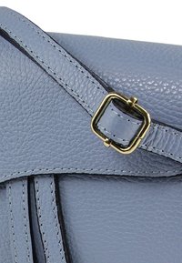 Lichtblauwe leren handtas met een gestructureerde afwerking, voorzien van een goudkleurige gesp en gestikte accenten.