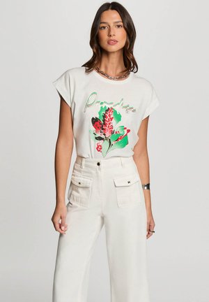 Off-white t-shirt med kortærmer, der har et farverigt blomstermotiv med ordet "Paradise" i grønt. Sæt sammen med højtaljede hvide bukser.