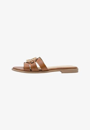 Sandales mules en cuir marron avec trois larges brides, une semelle plate et une boucle dorée sur la bride centrale. Texture lisse.