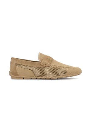 Mocassin beige à enfiler avec côtés en tissu mesh, garniture en daim et semelle plate, conçu pour un usage décontracté.