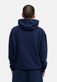 Dunkelblaues Kapuzensweatshirt mit lockerer Passform, großzügiger Kapuze und gerippten Bündchen, aus weichem Stoff gefertigt. Die Rückseite zeigt ein sauberes, einfaches Design.