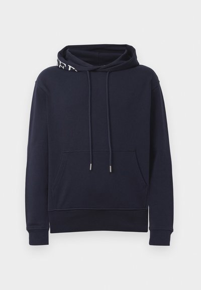 Tamsiai mėlynas sportinis džemperis su priekinėmis kišenėmis, su raišteliu reguliuojama kapučino, kuriame yra dalinė balta tekstas, ir gumbų apykaklėmis ir apačia.