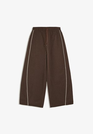 Pantalon ample marron à carreaux avec taille élastique, cordon, jambes larges et passepoil blanc vertical le long des coutures extérieures.