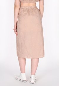 Beige geborduurde midi-rok met elastische tailleband, voorzien van bloemmotieven. Gecombineerd met witte hoge sneakers.