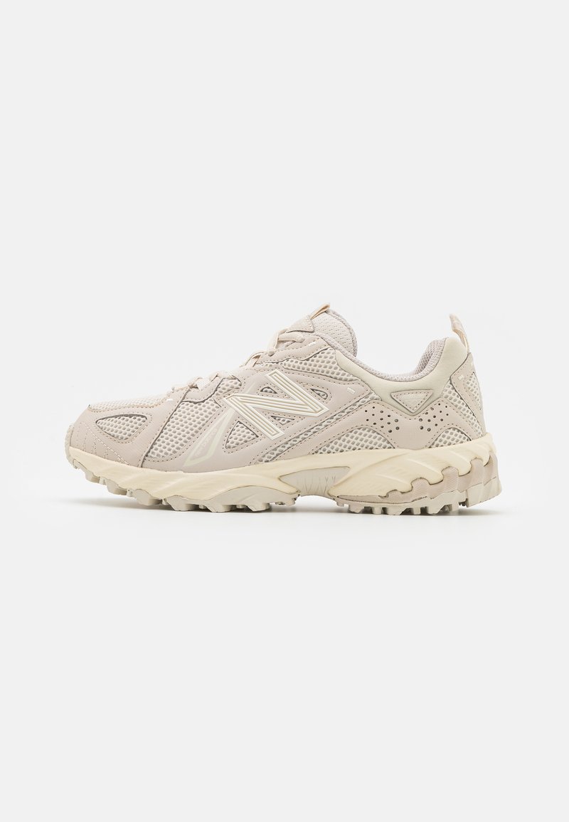 Beige New Balance terepfutó cipő hálós panelek, texturált talp és fűzős záródás jellemzi, a jobb oldalról látható profilban, fehér háttéren.