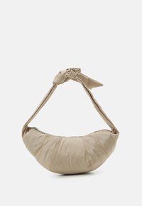 Beige axelväska med ett knutet tygband, puffsform och sydda detaljer längs kroppen. Tillverkad av mjukt, glansigt material.