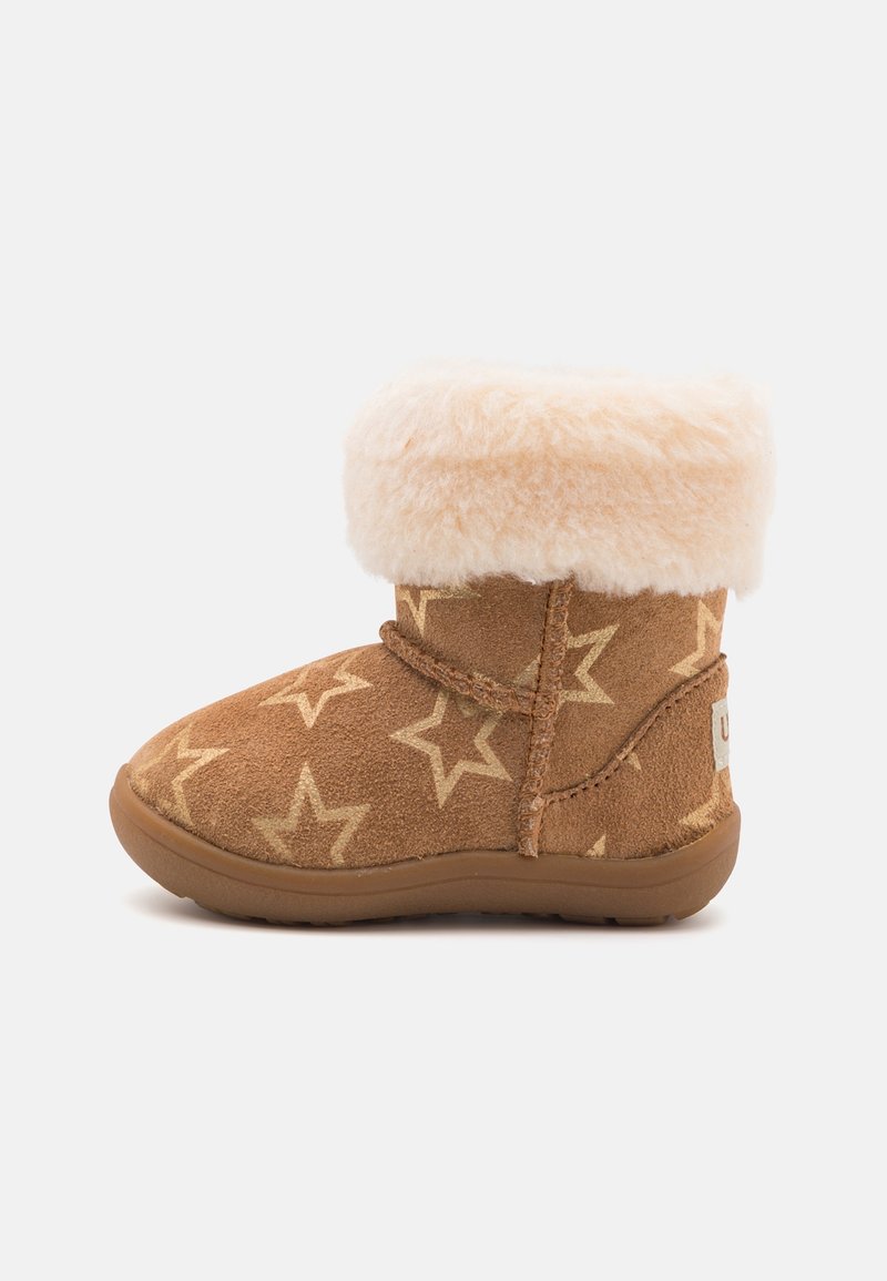 Botte marron pour tout-petit avec motifs d'étoiles crème et bordure en fourrure beige clair et duveteuse sur fond blanc.