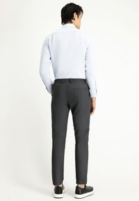 Lichtblauw, langemouwenshirt gecombineerd met donkergrijze broek met een gestructureerde stof en elastische tailleband, aangevuld met zwarte sneakers.