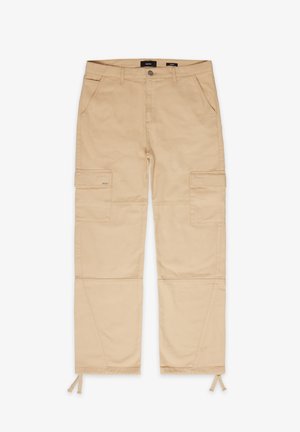 Beżowe spodnie cargo z dwiema przednimi kieszeniami i dwiema bocznymi kieszeniami. Posiadają elastyczne sznurki w kostkach oraz wzmocnione detale szwów.