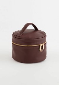 Round brown bag made of textured faux leather, featuring a top handle and a gold zipper with a double slider.