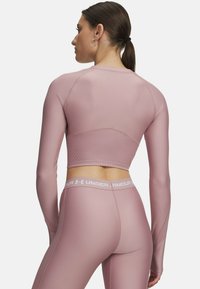 Lichtroze sporttop met lange mouwen en ribbelstructuur, gecombineerd met bijpassende high-waisted leggings met een gemerkte tailleband.