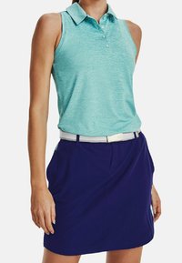Světle modré bezrukávové polo tričko s límečkem, třemi knoflíky a texturovanou tkaninou, které je doplněno sukní s elastickým pasem v námořnické barvě.