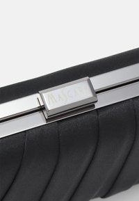 Czarna kopertówka z satyny o plisowanej fakturze i srebrnych elementach metalowych. Zapięcie ma prostokątną plakietkę z wygrawerowanym napisem "MASCARA".