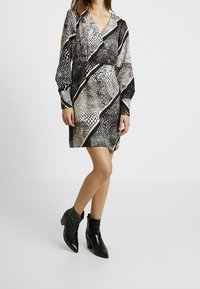 Short-sleeve dress with a black and white snake print design, featuring a v-neckline and contrasting diagonal stripes.