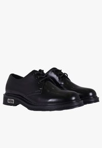 Scarpe eleganti in pelle nera con finitura liscia, punta tonda e design con lacci. Suola in gomma testurizzata con dettaglio del marchio sul tallone.