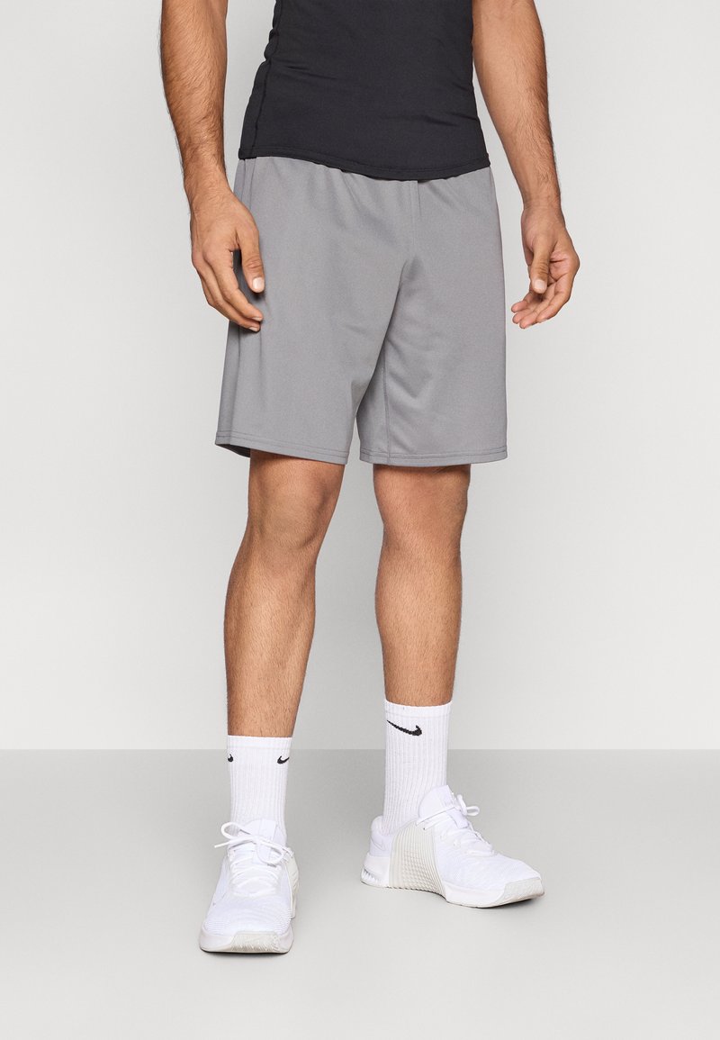 Γκρι αθλητικά σορτς με ελαστική μέση, συνδυασμένα με λευκά αθλητικά παπούτσια και λευκές κάλτσες μέχρι το γόνατο με μαύρο λογότυπο.