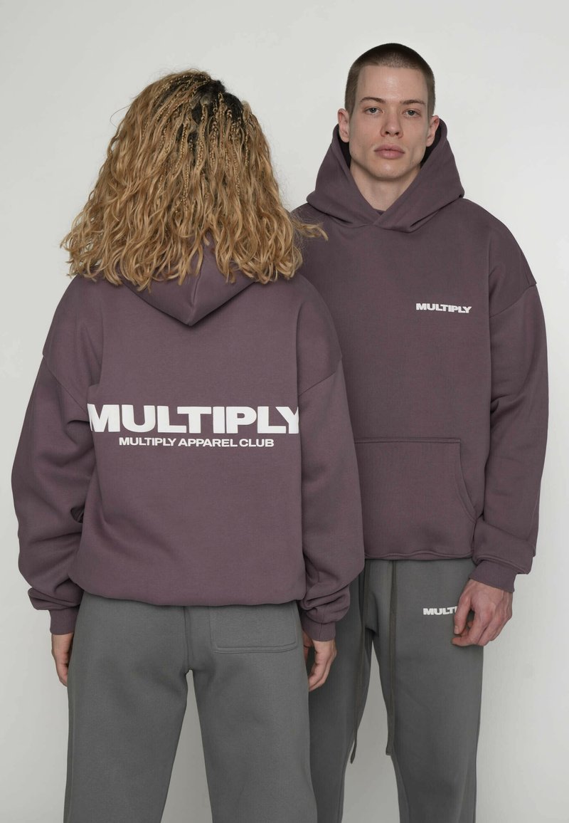 Bluzy z kapturem w ciemnym fioletowym kolorze, z białym napisem "MULTIPLY" z przodu i z tyłu. Materiał wydaje się miękki; luźny krój z kieszenią typu kangur.