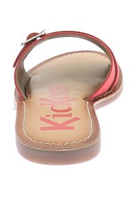 Sandaletta piatta rossa con una fascia sottile, design con punta aperta e soletta imbottita con il logo "Kickers" in rosa su uno sfondo beige.