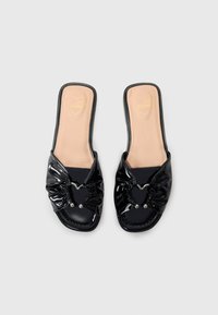 Fekete lakk slip-on szandál, gyűrött masni részlettel és szívformával, fémes díszítésekkel és nude színű, emblémázott talppal.