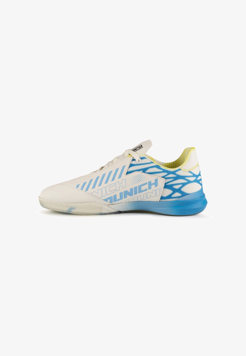 Chaussure de sport basse blanche et bleue avec lacets, talon en mesh à motifs et semelle bleue, avec le mot "Munich" sur le côté.