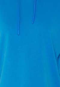 Modrá mikina s kapucí z měkké látky, s volným střihem, kapucí na šňůrku a proužkovanými detaily podél okrajů.