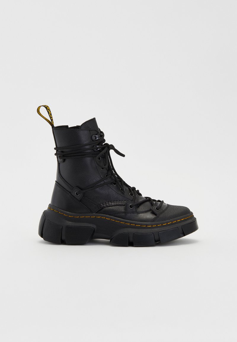Bottes noires à chevilles avec une semelle épaisse, en cuir texturé, bout rond et coutures jaunes. Elles présentent un laçage sur le devant et une languette en boucle.