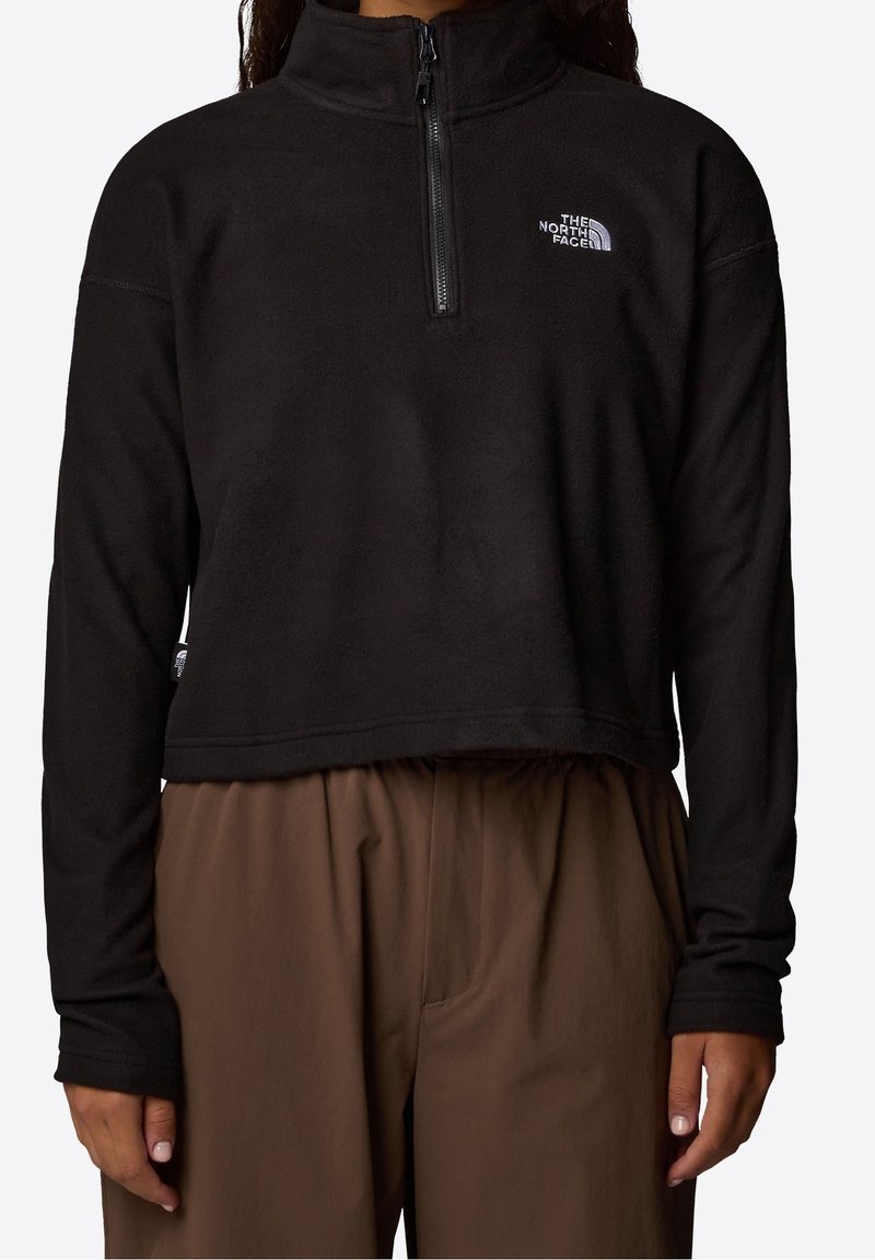 Czarny polarowy pulower z wysokim kołnierzem, zamkiem błyskawicznym o długości ćwierć oraz logo po lewej stronie klatki piersiowej. Posiada skrócony krój i elastyczny dół.