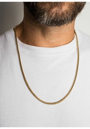 Guld kædedyse på en bar nakke over en hvid t-shirt. Kæden har sammenkoblede led med en glat, skinnende overflade.