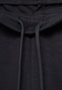 Close-up van zwarte hoodie stof met bijpassende zwarte koorden die door gestikte oogjes zijn gehaald.