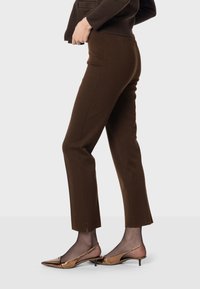 Bruna skräddarsydda byxor med smal passform, strukturert tyg och sidslitsar vid fållen. Matchas med bronsfärgade spetsiga slingback-häckar.