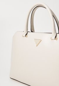 Borsa a tracolla in eco-pelle color crema con forma strutturata, dettagli in oro e logo impresso. Presenta manici robusti e bordi neri a contrasto.