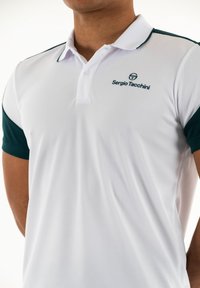 Biely polo tričko so zelenými rukávmi, obsahujúce trojradový gombíkový zapínanie a vyšitý logo na hrudi. Vyrobené z textúrovaného, priedušného materiálu.