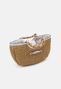 Sac à main tressé marron avec bordure blanche, poignées style bambou, ferrures dorées et logo "Guess" sur le devant, photographié sur fond blanc.