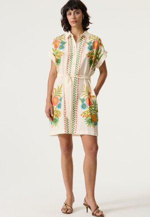 Robe à boutons couleur crème avec broderies florales vives en orange, vert et bleu. Comprend une ceinture et des manches courtes. Texture lisse.