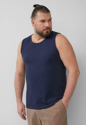 Donkerblauw mouwloos tanktop met een gladde textuur. Ronde halslijn en een subtiele merklogo op de borst. Combinatie met beige broeken.