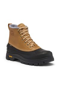 Bottes basses en cuir marron imperméable avec doublure en polaire grise, semelle intermédiaire en caoutchouc noir, œillets métalliques et semelle extérieure Vibram antidérapante.