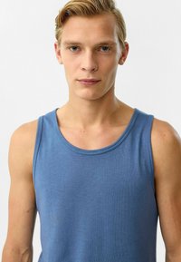 Blauwe katoenen tanktop met een ronde halslijn, dunne schouderbanden en een zachte textuur, met een eenvoudig, minimalistisch ontwerp.