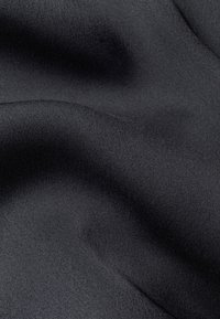 Musta satiiniharso, jolla on sileä ja kiiltävä pinta. Materiaali laskeutuu lempeästi, muodostaen pehmeitä kaaria ja hienovaraisia aaltoja.