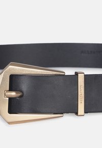 Zwarte leren riem met een grote, hoekige gouden gesp en een rechthoekige hardware accent met ingegraveerde merknaam. Gladde textuur.