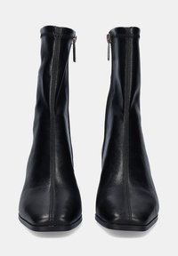 Botas de cuero negras hasta el tobillo con un diseño ajustado, puntera cuadrada, cremalleras laterales y costuras verticales para textura. Acabado suave con tacón bajo.