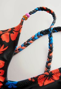 Czarny biustonosz bikini z czerwono-niebieskim wzorem kwiatowym, z plecionymi ramiączkami w kolorze czarnym, czerwonym i niebieskim, ozdobiony kolorowymi koralikami.