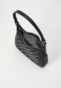 Sac à main en cuir noir avec un motif texturé, fermeture à glissière et une sangle unique réglable. L'intérieur présente un imprimé contrastant.
